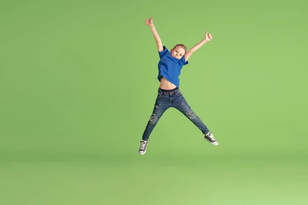 Счастливый мальчик играет и веселится на зеленом студийном фоне, эмоции — стоковое фото