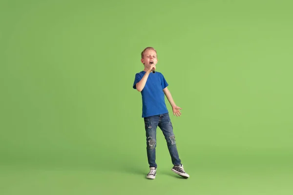Šťastný chlapec hrát a bavit se na zeleném pozadí studia, emoce — Stock fotografie