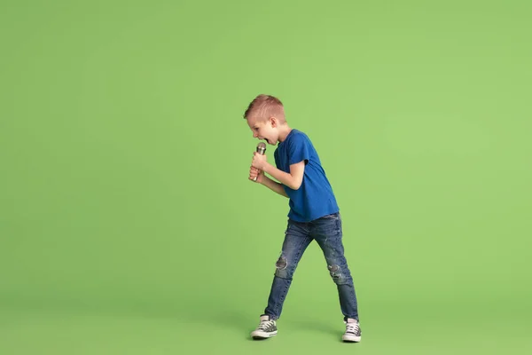 Niño feliz jugando y divirtiéndose en el fondo del estudio verde, emociones —  Fotos de Stock