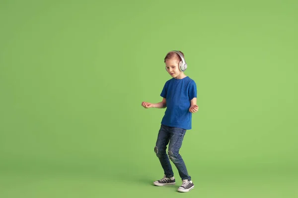 Niño feliz jugando y divirtiéndose en el fondo del estudio verde, emociones — Foto de Stock