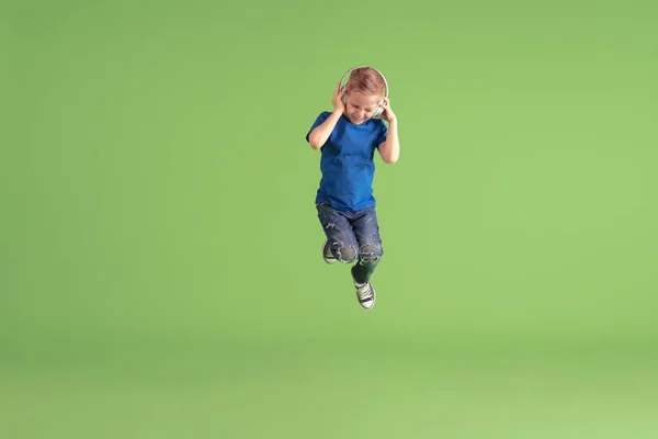 Niño feliz jugando y divirtiéndose en el fondo del estudio verde, emociones — Foto de Stock