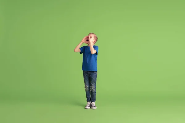 Niño feliz jugando y divirtiéndose en el fondo del estudio verde, emociones — Foto de Stock