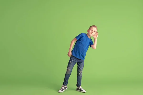 Šťastný chlapec hrát a bavit se na zeleném pozadí studia, emoce — Stock fotografie