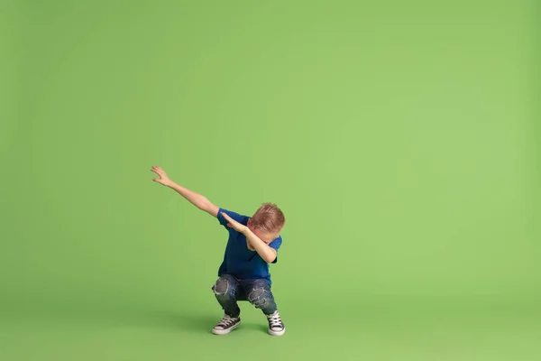 Ευτυχισμένο αγόρι παίζει και διασκεδάζει στο πράσινο φόντο στούντιο, συναισθήματα — Φωτογραφία Αρχείου