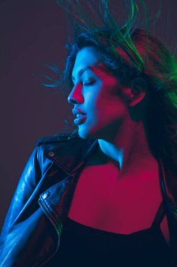 Güzel kadın portresi. Stüdyonun arka planında koyu renk neon ışıklarıyla saç üflüyor.