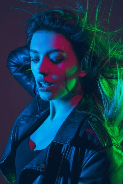 Gambar wanita cantik dengan rambut bertiup di latar belakang studio gelap dalam warna-warni cahaya neon — Stok Foto