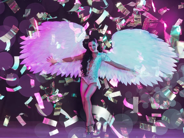 Jeune danseuse aux ailes d'anges au néon sur fond noir en confettis volants — Photo