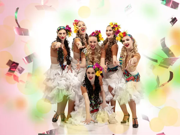 Jovens mulheres bonitas em trajes de carnaval em luzes de néon coloridas no fundo branco em voando confete — Fotografia de Stock