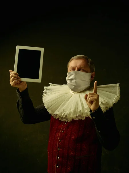 코로나 바이러스에 대한 보호용 마스크를 쓰고 어두운 배경에서 중세 기사로서의 노인 — 스톡 사진