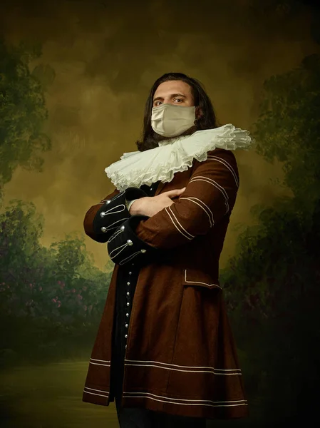 Joven caballero medieval sobre fondo oscuro con máscara protectora contra el coronavirus —  Fotos de Stock