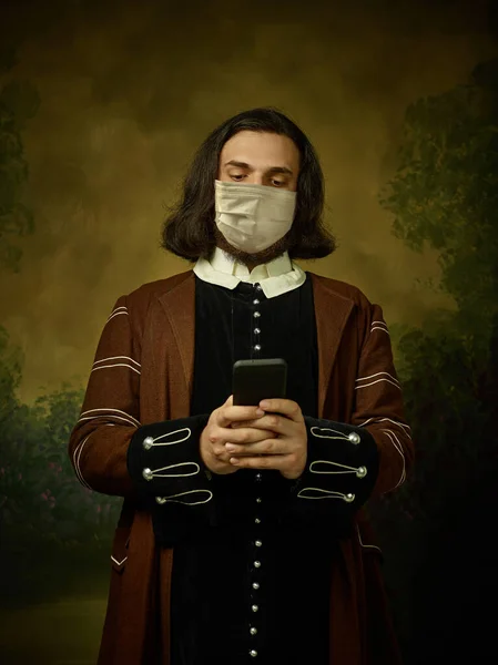 若いです男として中世の騎士暗い背景に身に着けている保護マスクに対するコロナウイルス — ストック写真
