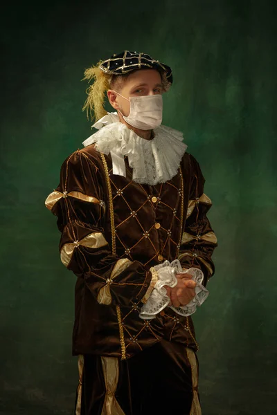 Fiatal férfi, mint egy középkori lovag sötét háttér visel védő maszkot a koronavírus ellen — Stock Fotó