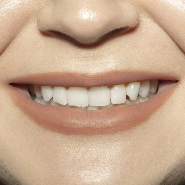 Close-up female mouth with natural nude gloss lips make-up. Cosmetology, dentistry and beauty care, emotions