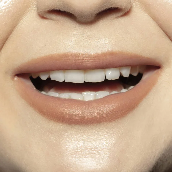 Close-up female mouth with natural nude gloss lips make-up. Cosmetology, dentistry and beauty care, emotions