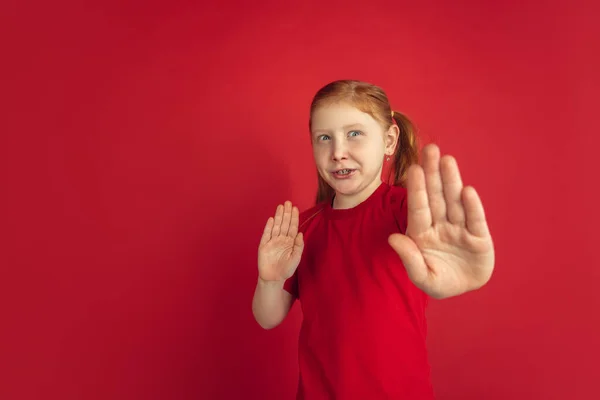 Vit liten flicka porträtt isolerad på röd studio bakgrund, känslor koncept — Stockfoto