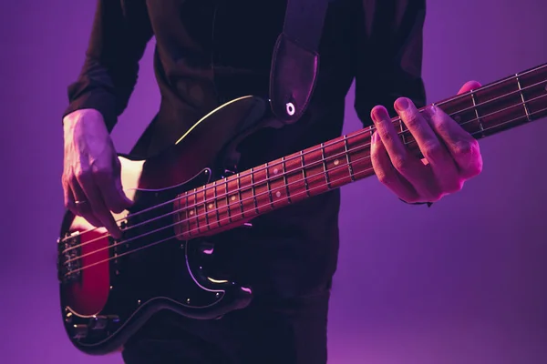 Junger kaukasischer Musiker spielt Gitarre im Neonlicht auf lila Hintergrund — Stockfoto