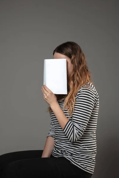 Feliz dia do livro mundial, leia para se tornar outra pessoa mulher cobrindo rosto com livro enquanto lê em fundo cinza — Fotografia de Stock