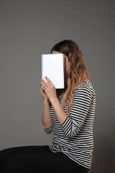 Feliz dia do livro mundial, leia para se tornar outra pessoa mulher cobrindo rosto com livro enquanto lê em fundo cinza — Fotografia de Stock