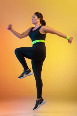 Genç Kafkasyalı artı boyut kadın modeller eğimli turuncu arka plan eğitimi alıyorlar.