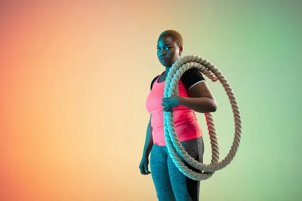 Young african-american plus size female models training on gradient background