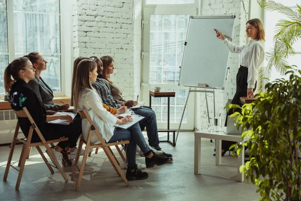 Ponente mujer caucásica dando presentación en salón en taller universitario o de centro de negocios — Foto de Stock