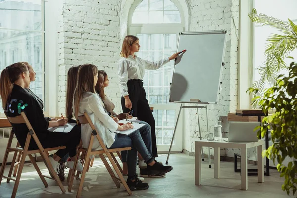 Ponente mujer caucásica dando presentación en salón en taller universitario o de centro de negocios — Foto de Stock