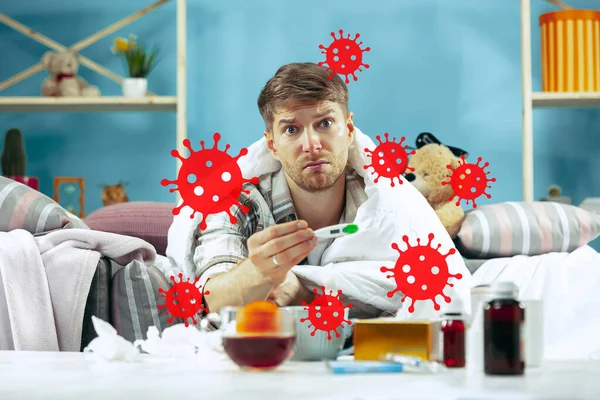 Mladý muž se bojí šíření koronaviru a celosvětových případů, nevolnost, horečka — Stock fotografie