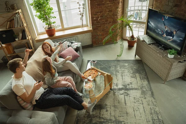 Famille passer du bon temps ensemble à la maison, semble heureux et excité, manger de la pizza, regarder le match de football féminin — Photo