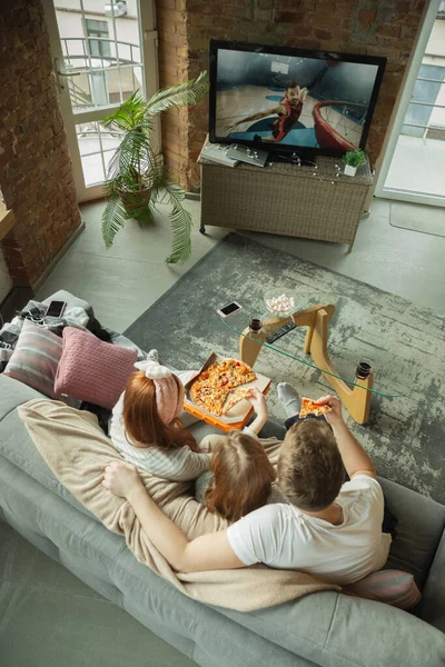 Familia pasar un buen tiempo juntos en casa, se ve feliz y emocionado, comer pizza, ver el partido de baloncesto — Foto de Stock