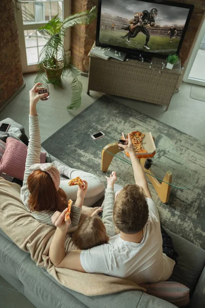 家族は家で一緒に楽しい時間を過ごします,幸せと興奮して見えます,ピザを食べます,サッカーの試合を見ます — ストック写真