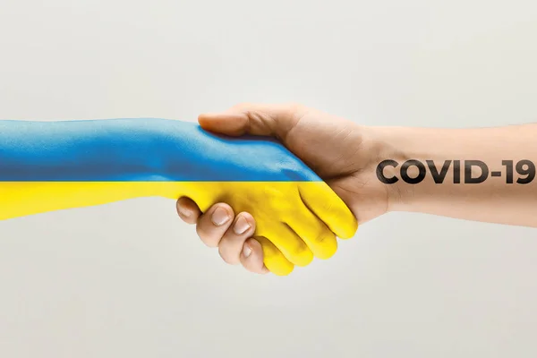 乌克兰国旗上的人的手和珊瑚色的手-病毒传播的概念 — 图库照片