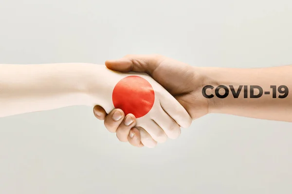 Human hands colored in flag of Japan and coronavirus - concept of spreading of virus — Stock Photo, Image