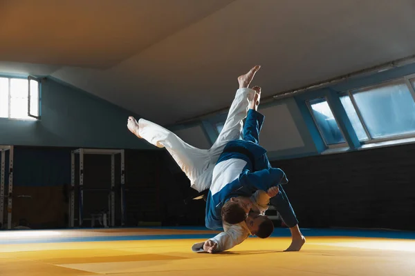 Kimono giymiş iki genç judo dövüşçüsü spor salonunda dövüş sanatları eğitiyorlar. — Stok fotoğraf