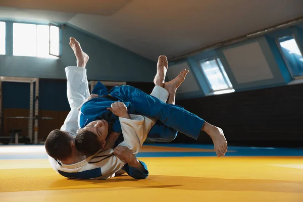 Kimono giymiş iki genç judo dövüşçüsü spor salonunda dövüş sanatları eğitiyorlar. — Stok fotoğraf