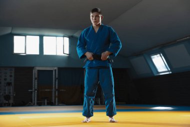 Kimonolu genç judo dövüşçüsü spor salonunda kendine güvenen, güçlü ve sağlıklı.