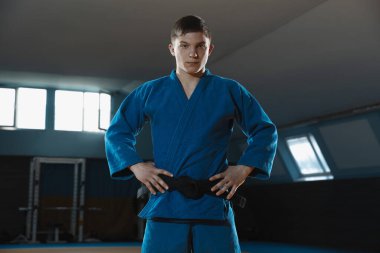 Kimonolu genç judo dövüşçüsü spor salonunda kendine güvenen, güçlü ve sağlıklı.