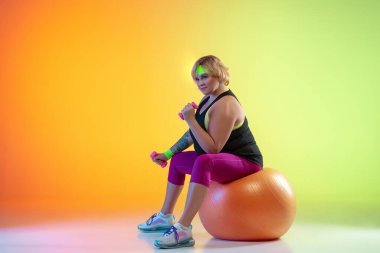 Genç Kafkasyalı artı boyut kadın modeller eğimli turuncu arka plan eğitimi alıyorlar.