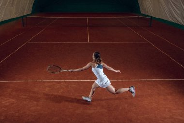 Spor sahasında tenis oynayan beyaz, profesyonel bir bayan.