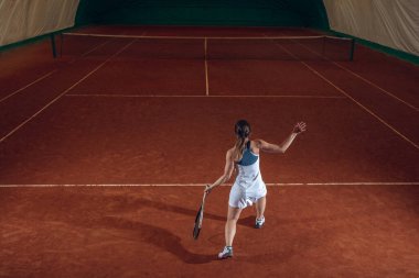 Spor sahasında tenis oynayan beyaz, profesyonel bir bayan.