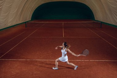 Spor sahasında tenis oynayan beyaz, profesyonel bir bayan.