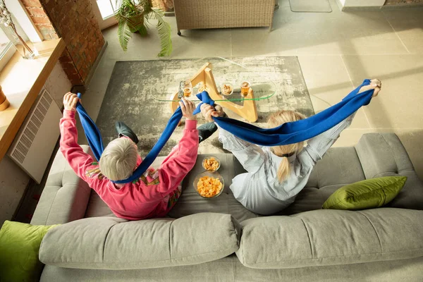 Excited family watching football, sport match at home, grandma and daughter