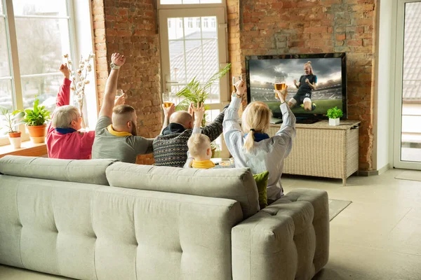 Excited family watching female football, sport match at home
