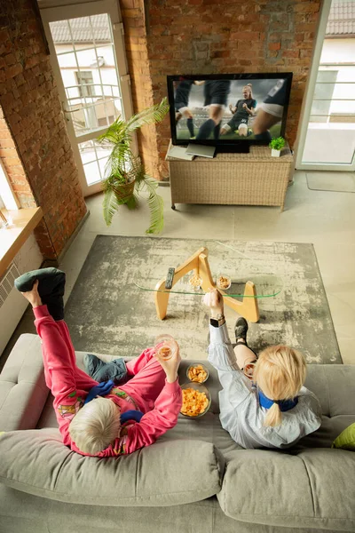 Excited family watching football, sport match at home, grandma, mother and son