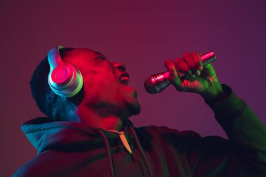 Afro-amerikan portresi ve kulaklıkları neon ışıklarıyla izole edilmiş.