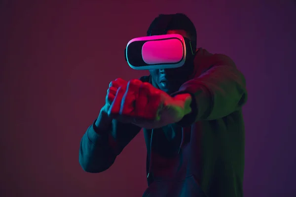 Ritratto di uomo afro-americano in cuffia VR isolato su sfondo gradiente da studio in luce al neon — Foto Stock