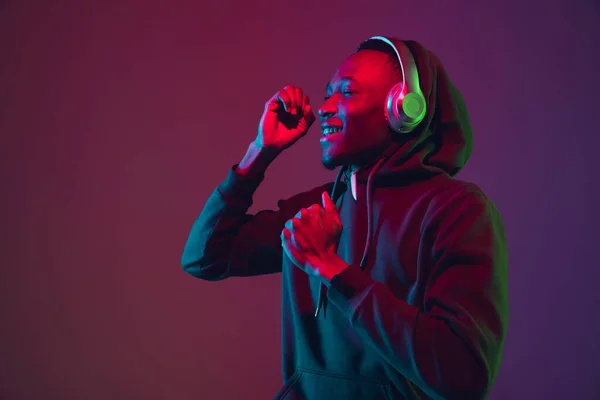 Retrato de hombre afroamericano con auriculares aislados sobre fondo de estudio degradado en luz de neón —  Fotos de Stock