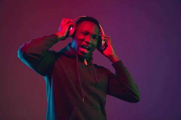 Retrato de hombre afroamericano con auriculares aislados sobre fondo de estudio degradado en luz de neón —  Fotos de Stock