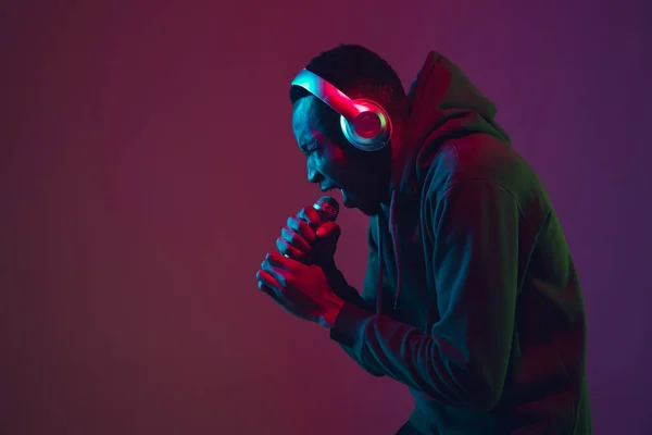 Retrato de hombre afroamericano con auriculares aislados sobre fondo de estudio degradado en luz de neón —  Fotos de Stock