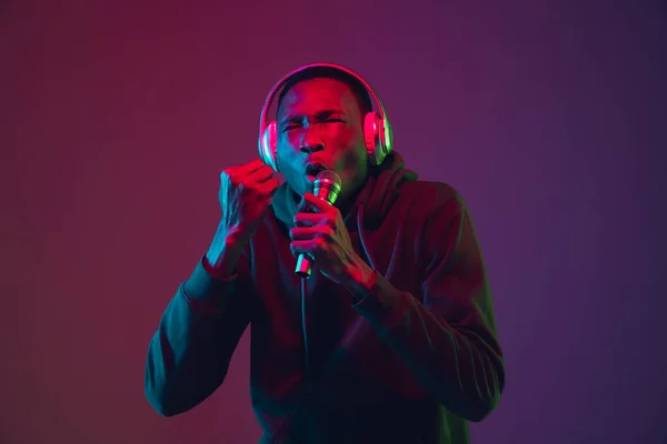 Retrato de hombre afroamericano con auriculares aislados sobre fondo de estudio degradado en luz de neón —  Fotos de Stock