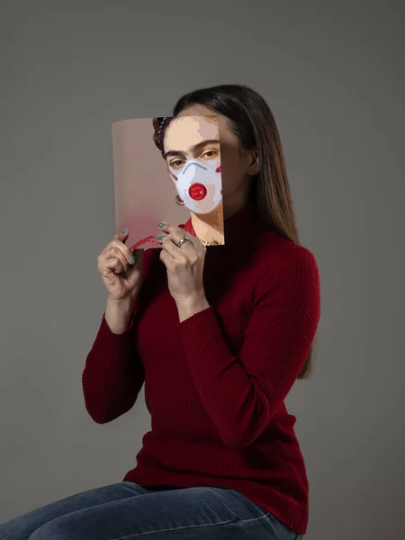 Sicher sein und lesen, um jemand anderes zu werden - Frau verdeckt Gesicht mit Buch in Gesichtsmaske, während sie auf grauem Hintergrund liest — Stockfoto
